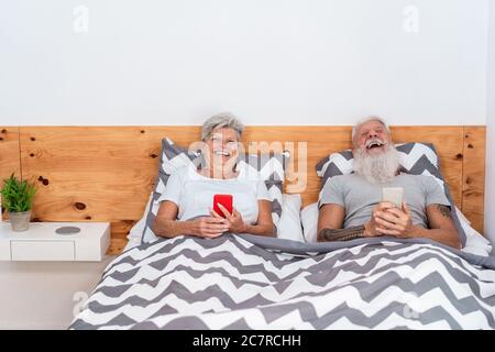 Glückliches Seniorenpaar beim gemeinsamen Lachen Videos mit Mobiltelefonen ansehen - Ältere Menschen haben Spaß mit Smartphones zu Hause - Technologie, joyf Stockfoto