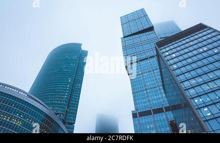 Wolkenkratzer des Bürozentrums aus Glas und Beton in dichten Nebelwolken. Stockfoto