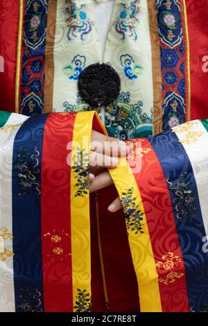 Nahaufnahme von Händen, Ärmeln und komplizierten Mustern vietnamesischer traditioneller königlicher Seidenroben mit den Farben Gelb, Blau, Rot und Weiß, die von Queen getragen werden Stockfoto