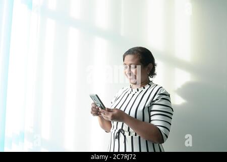 Glückliche indische ethnische Geschäftsfrau lächelnd Blick auf Smartphone, SMS auf Handy oder Handy-Spiele. Stockfoto