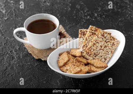 Cerealien-Kekse und eine Tasse Kaffee auf dunklem Hintergrund Stockfoto