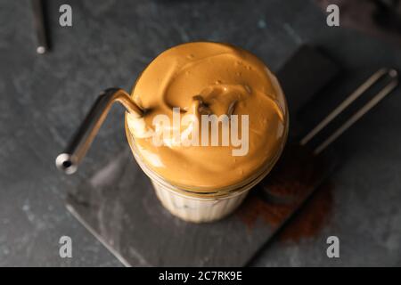 Glas leckeren Dalgona Kaffee auf dunklem Hintergrund Stockfoto