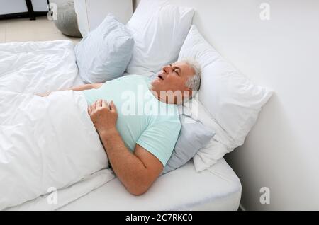 Reifer Mann schnarcht während schlafen im Bett. Apnoe-Problem Stockfoto