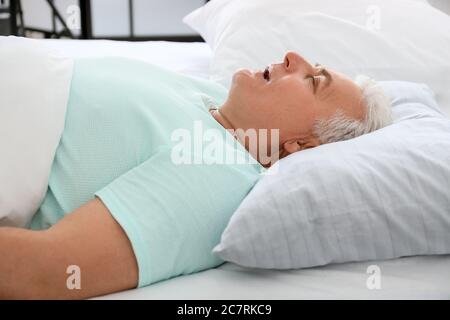 Reifer Mann schnarcht während schlafen im Bett. Apnoe-Problem Stockfoto