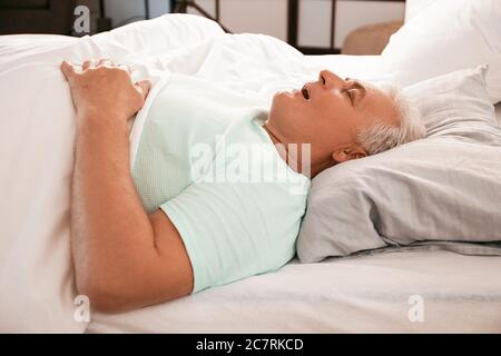 Reifer Mann schnarcht während schlafen im Bett. Apnoe-Problem Stockfoto