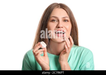 Schöne junge Frau mit Lippenbalsam auf weißem Hintergrund Stockfoto