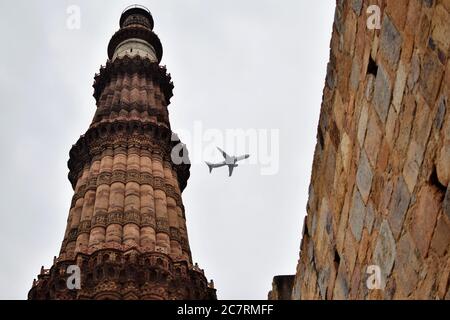 Flugzeug fliegen in den bewölkten Himmel während der Tageszeit in der Nähe von Qutub Minar in Delhi Indien, Flugzeug fliegen hoch in den Himmel Stockfoto