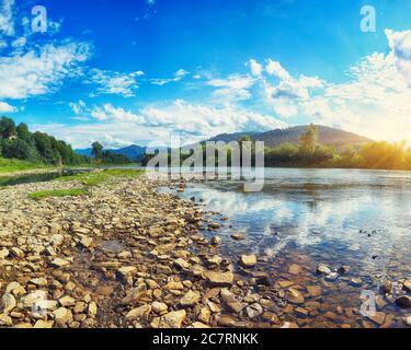 Gebirgsfluss von Wasser in den Felsen mit blauem Himmel. Klare Fluss mit Felsen führt in Richtung Berge von Sonnenuntergang beleuchtet. Karpaten. Ukraine Stockfoto