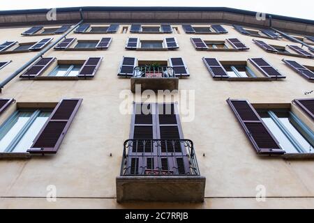 Vintage-Fenster mit Fensterläden über der gelben Hauswand Stockfoto