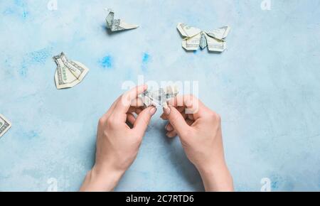 Frau, die Origami-Figuren aus Dollar-Banknoten am Tisch Stockfoto