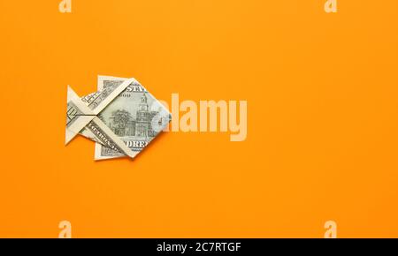 Origami-Fisch aus Dollar-Banknote auf farbigem Hintergrund Stockfoto