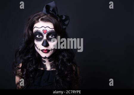 Junge Frau mit Halloween Totenkopf Make-up auf schwarzem Hintergrund Stockfoto