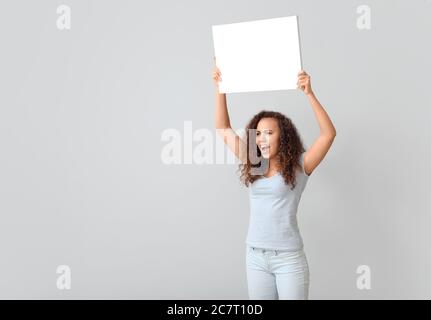 Wütend protestierende afroamerikanische Frau mit Plakat auf hellem Hintergrund Stockfoto