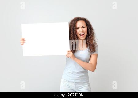 Wütend protestierende afroamerikanische Frau mit Plakat auf hellem Hintergrund Stockfoto