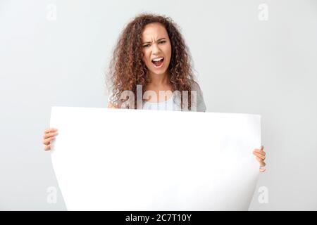 Wütend protestierende afroamerikanische Frau mit Plakat auf hellem Hintergrund Stockfoto