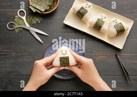 Frau bereitet traditionelle japanische onigiri auf dem Tisch Stockfoto