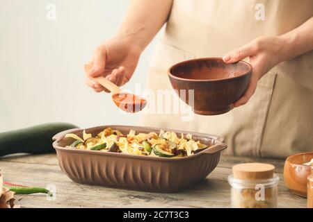 Frau bereitet leckere Pasta in Backform auf dem Tisch Stockfoto