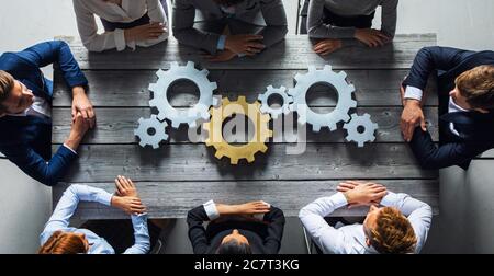 Gruppe von Geschäftsleuten, die sich auf dem Tisch am Arbeitsplatz in silberner und goldfarbener Ansicht zusammenschließen Stockfoto