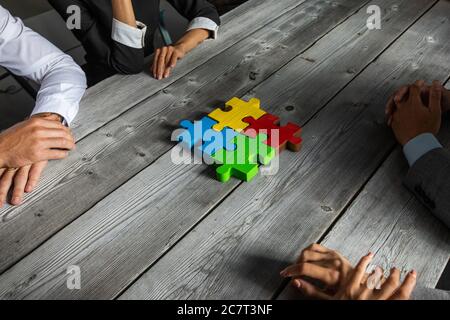 Business People Team sitzen um Besprechungstisch Finishing Montage Farbe Puzzle Stücke Einheit Zusammenarbeit Ideen Konzept Stockfoto