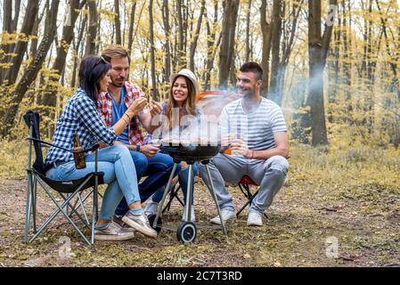 Junge fröhliche Freunde bereiten Grill im Freien Stockfoto