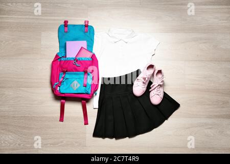 Stilvolle Schuluniform mit Rucksack auf Holz- Hintergrund Stockfoto