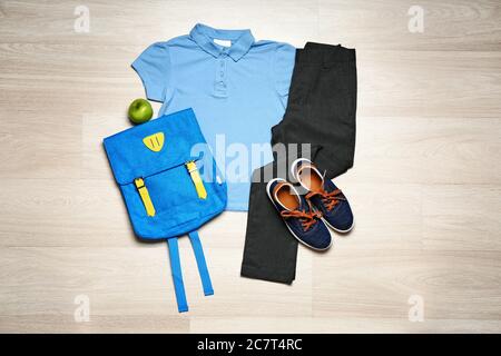 Stilvolle Schuluniform mit Rucksack auf Holz- Hintergrund Stockfoto