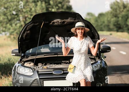 Junge Frau in der Nähe kaputtes Auto auf der Straße Stockfoto