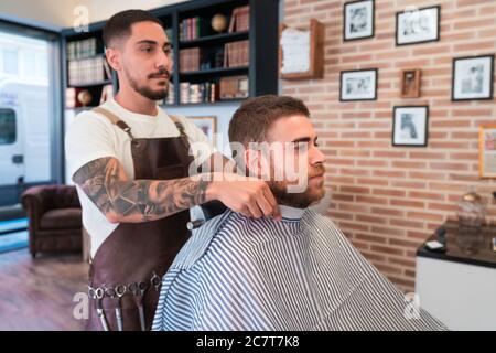 Nahaufnahme eines Friseurs mit Tätowierungen, die einen Nackenstreifen setzen Um den Hals des Kunden Stockfoto