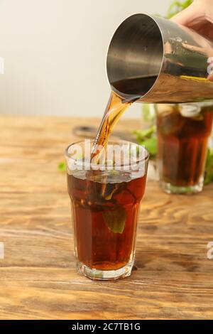 Gießen von leckeren Cuba Libre Cocktail in Glas auf dem Tisch Stockfoto