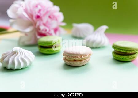Eine französische süße Delikatesse, bunte Makronen Varietät Nahaufnahme mit Blumen auf weißem Hintergrund. Leckere Makronen bunte Textur. Stockfoto