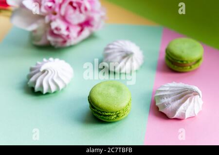 Eine französische süße Delikatesse, bunte Makronen Varietät Nahaufnahme mit Blumen auf weißem Hintergrund. Leckere Makronen bunte Textur. Stockfoto