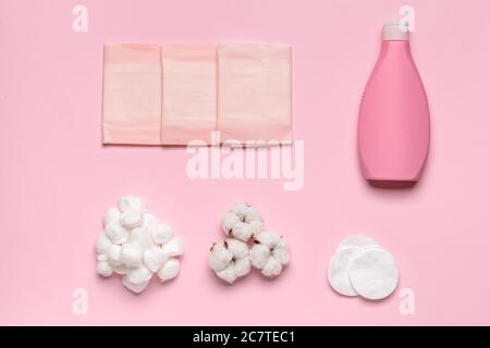 Baumwollbälle mit kosmetischen und Menstruationskissen und eine Flasche Shampoo auf farbigem Hintergrund Stockfoto