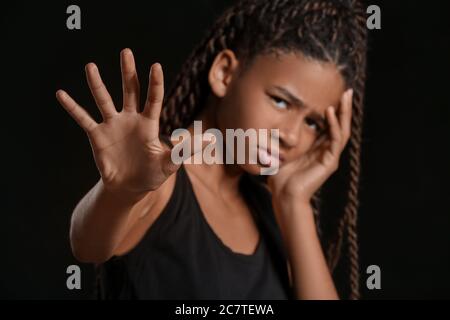 Trauriges afroamerikanisches Mädchen auf dunklem Hintergrund. Stoppen Sie Rassismus Stockfoto