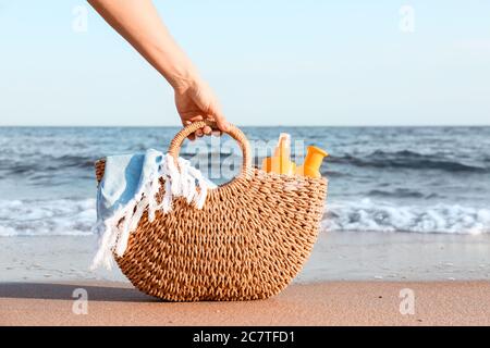 Frau mit Sonnenschutzcreme in der Tasche am Strand Stockfoto