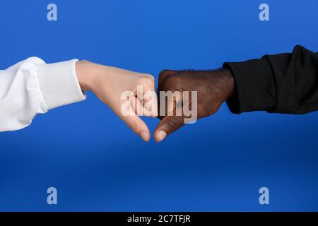 Kaukasische Frau und afroamerikanischen Mann stoßen Fäuste auf Farbe Hintergrund. Rassismus-Konzept Stockfoto