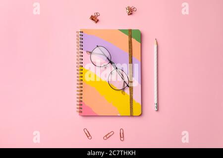 Stilvolles Notizbuch mit Bleistift und Brillen auf farbigem Hintergrund Stockfoto