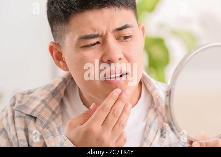 Asiatische Mann mit kalten Wunden suchen im Spiegel Stockfoto