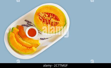 Süße Melone in Scheiben geschnitten mit Honig und Lavendel auf Eine weiße Platte Stockfoto