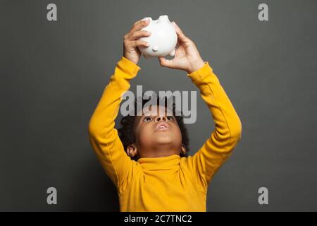 Afroamerikanischer Junge mit leerem Sparschwein Stockfoto