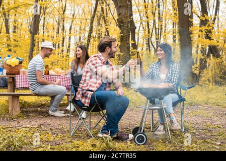 Gruppe von jungen Freunden mit einem Barbecue-Picknick in einem park an einem sonnigen Tag Stockfoto