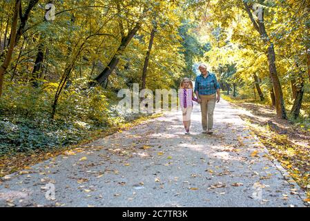Großmutter und ihre süße Enkelin gehen durch einen Pfad hinein Ein Park Stockfoto
