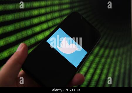 Viersen, Deutschland - 9. Juli. 2020: Blick auf Handy mit twitter-Logo von Hand halten. Bildschirm mit Tunnel von binären Code-Nummern Hintergrund.(selektiv Stockfoto