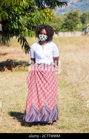 Frau trägt eine lokale handgemachte Gesichtsmaske aus traditionellem afrikanischen Stoff Sarong zum Schutz vor Corona-Virus Stockfoto