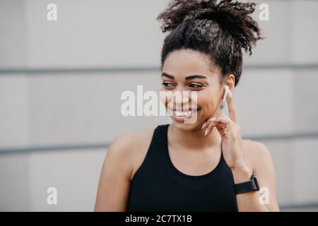 Musik und Laufen. Mädchen mit Fitness-Tracker setzt drahtlose moderne Kopfhörer Stockfoto