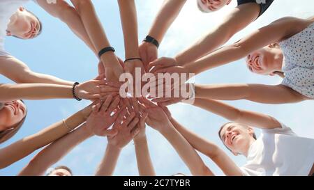 Fröhliche freundliche Freunde richten ihre Hände in der Mitte aus. Teamwork-Konzept. Stockfoto