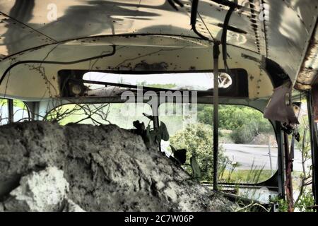 Innenansicht eines alten verlassenen zerstörten Busses in einem Feld voller Müll Stockfoto