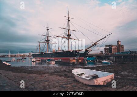 HMS Warrior vertäute in Portsmouth mit einem alten Fischerboot Im Vordergrund am Kai Stockfoto