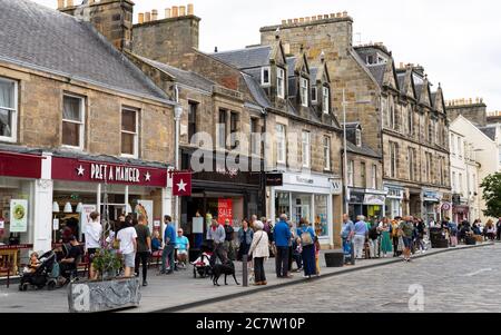 Blick auf die Menschen und Geschäfte entlang der belebten Market Street im Zentrum von St Andrews, Schottland, Großbritannien Stockfoto