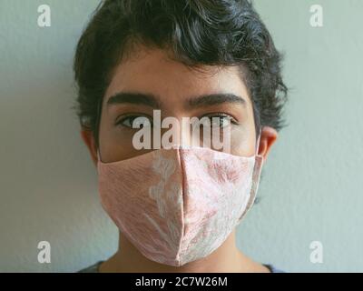 Kurzhaarige Frau mit rosa Gesichtsmaske und Blick auf die Kamera. Stockfoto