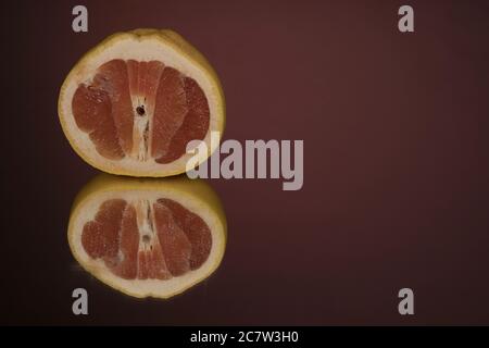 Halb transparente Grapefruitscheibe auf einem Hintergrund mit Spiegelung. Stockfoto